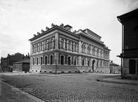 Helsingfors stadsbibliotek, huvudbiblioteket, Rikhardsgatan 3. Byggnaden omges av låga trähus. 