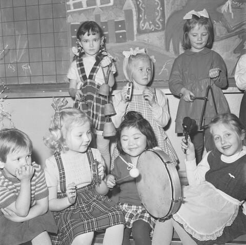 Ryhmä lapsia musisoi. Istumassa, tamburiinia soittamassa japanilaistyttö Suomi Sakai.
