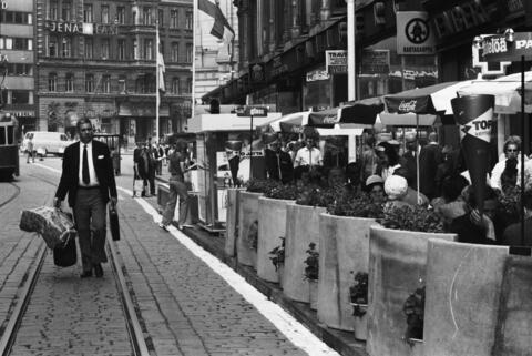 Alexandersgatan 21. En man promenerar med händerna fulla förbi ett gatukafé framför Tallbergska huset på öppningsdagen av Alexandersgatans gågatuförsök.