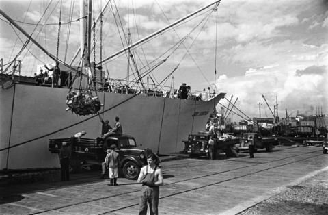 Lasten av ett handelsfartyg håller på att lossas med vinscher till lastbilsflak i Sörnäs hamn.
