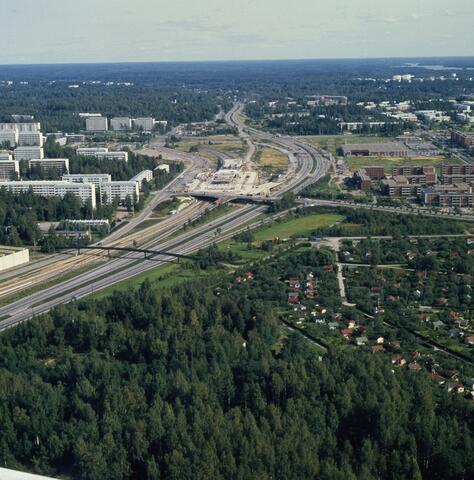 Flygbild över Östra centrums bygge längs med Österleden. Till höger av Österleden finns redan nya våningshus. På stället av metrostationen och köpcentret finns ännu ett bygge.