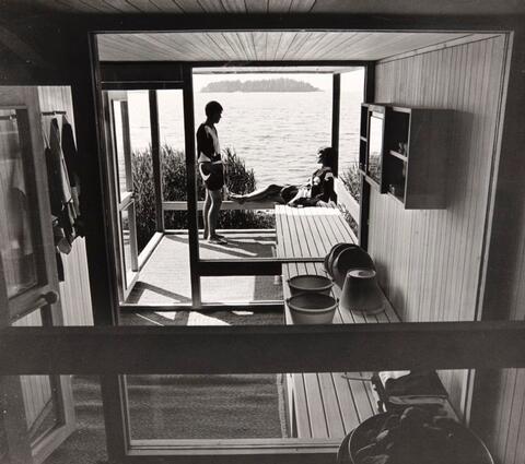 Interiör från bastun och två bastubadare på terrassen med ett havslandskap i bakgrunden.