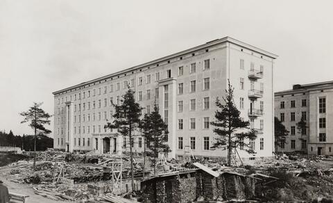 Laakson sairaalarakennus, edessä puita ja puretun autotallin työmaa