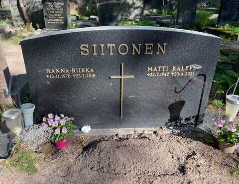 Yksinkertainen musta graniittipaasi, jonka yläreunassa lukee SIITONEN ja keskellä on metalliristi. Ristin vasemmalla puolella teksti HANNA-RIIKKA s. 13.11.1970, k. 23.7.2018 ja oikealla puolella MATTI KALEVI s. 23.7.1942, k. 23.4.2021
