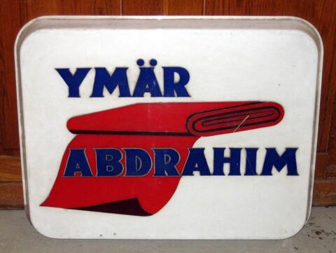 Valkea muovinen suorakaide, jonka kulmat pyöristetyt. Valkealla pohjalla kuva punaisesta kangaspakasta sekä sinisellä teksti: YMÄR ABDRAHIM