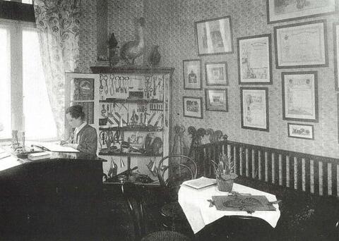 Keskellä on avoin nurkkakaappi täynnä instrumentteja. Vasemmalla istuu nainen kirjoituspöydän ääressä ikkunan luona. Oikealla on sohva.