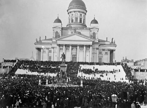 Talvinen kuva Senaatintorilta. Etualalla Aleksanteri II:n patsas ja taustalla Nikolainkirkko. Senaatintorilla ja Nikolainkirkon ympäristössä sankka ihmisjoukko