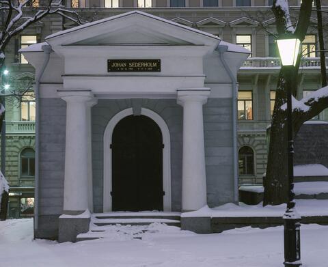 Foto av en liten stenbyggnad, dekorerad i nyklassisk stil. Ovanför dörren står det Johan Sederholm.