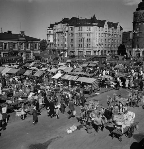 Näkymä Hakaniemen torille lintuperspektiivistä vuonna 1940. Tori on tupaten täynnä pieniä myyntikojuja ja ihmisiä.