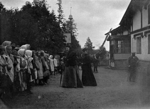 Aurora Karamzin utanför Träskända folkskola som hon grundat. En lång rad barn hälsar på henne. 