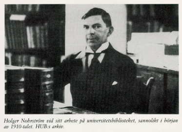 Tummaan pukuun ja solmioon pukeutunut mies istuu kirjoituspöydän ääressä.