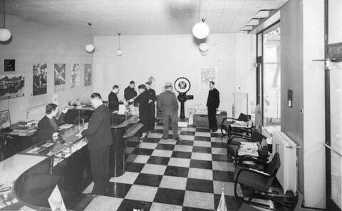 Henkilökuntaa ja asiakkaita funkkistyylisessä matkatoimistossa 1930-luvun lopulla.