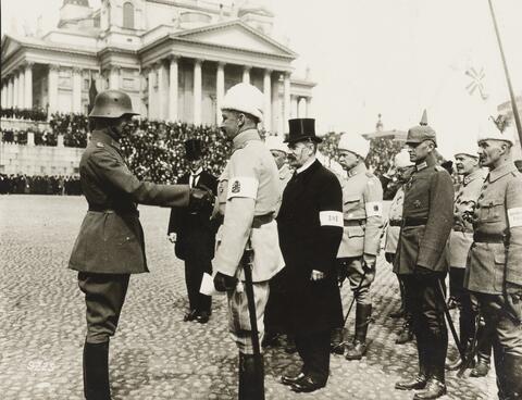 Mannerheim klädd i vitt skakar hand med en tysk officer på Senatstorget.