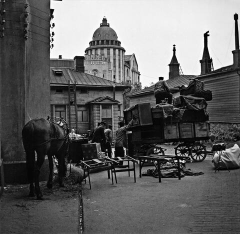 Ihmisiä muuttopuuhissa Läntinen Heikinkatu 24:n (Mannerheimintie 18:n kohdalla). Ihmiset lastaavat sisäpihalla laatikoita hevoskärryjen selkään.