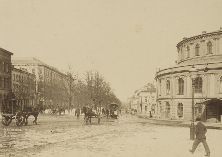 Hästfordon och fotgängare framför Svenska teatern. Bilden har tagits på vårvintern.