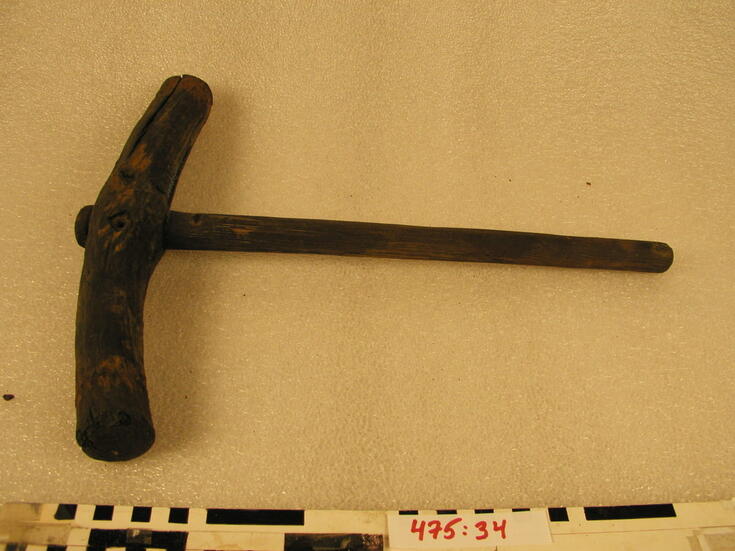 Puusta tehty nuija, jonka varren pituus on 44 cm ja pään pituus on 37 cm ja halkaisija 4,5 cm.