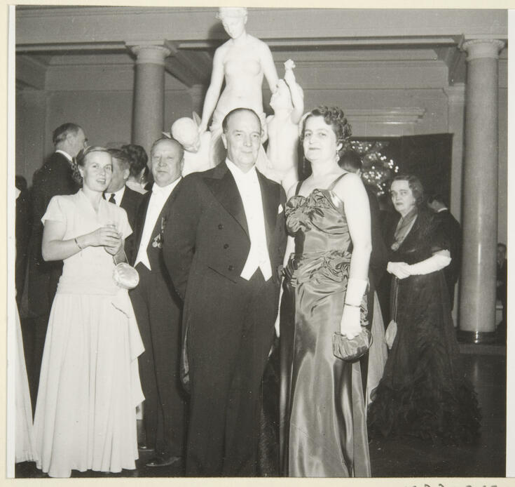 Iltapukuisia ihmisiä Presidentinlinnassa. Taustalla marmoriveistos.