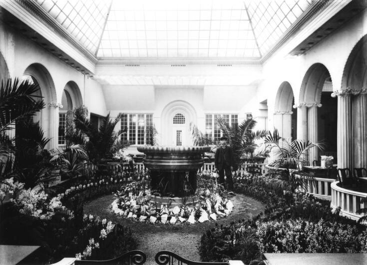 Katettu sisäpiha, jossa on eksoottisia kasveja ja suihkulähde.