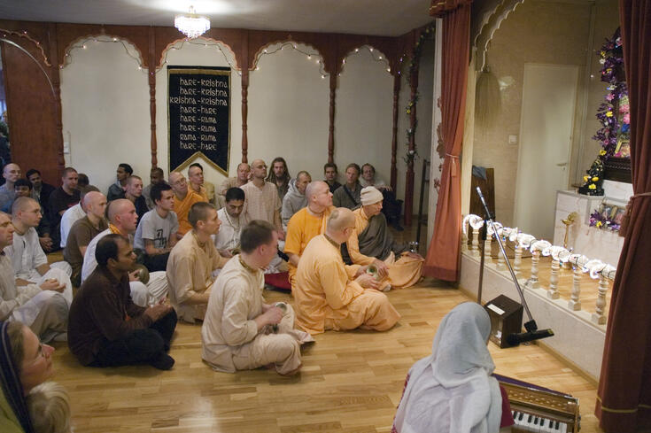 En försångare ackompanjerar sång på indiskt harmonium. I ceremonin deltar bhaktor, det vill säga finländare och invånare i templet som är hängivna Krishna samt indiskfödda vänner av templet. Gräsviksgatan 24.