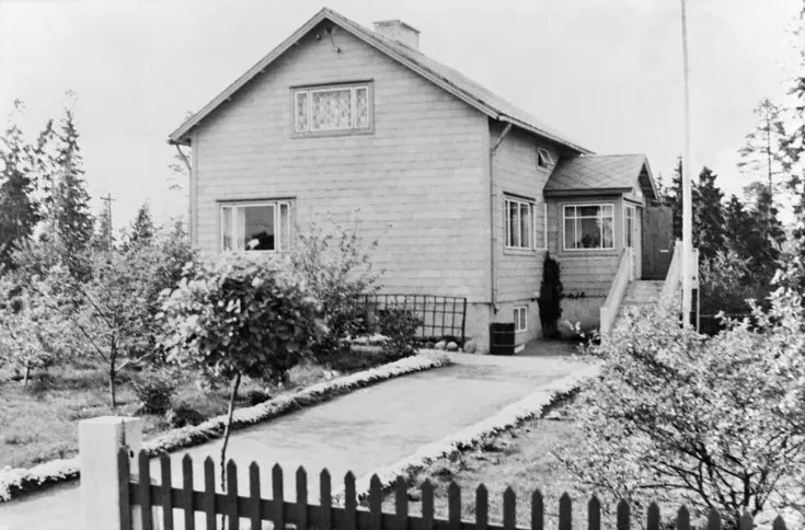Ett frontmannahus omgivet av en sommarträdgård. Framför huset finns en flaggstång.