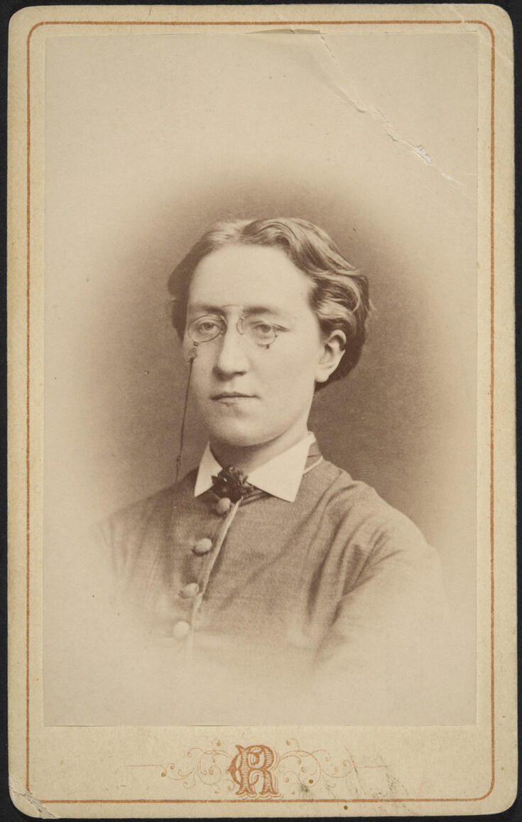 Rintakuva naisesta, jolla on kaulaan asti napitettu puku ja nenälasit.