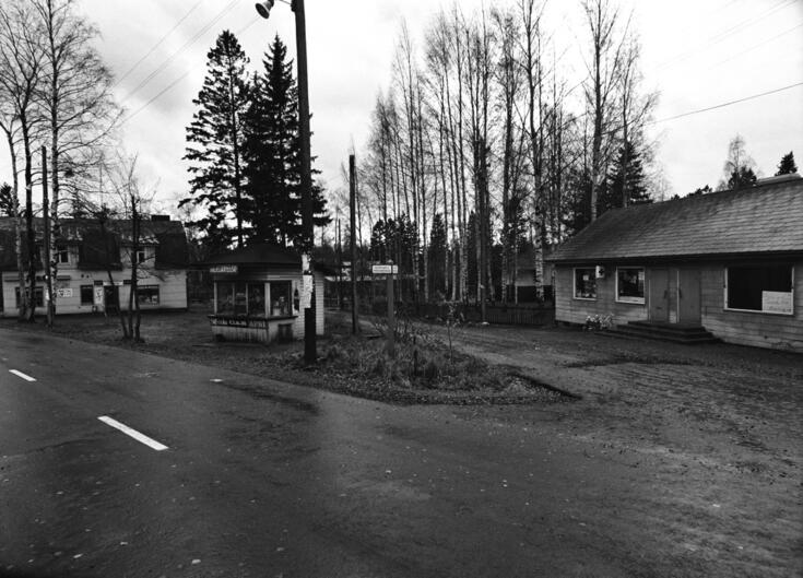 Näkymä syksyiseltä Puistolantieltä (nyk. Puistolantorilta) Karrintien (nyk. Iivarinpolun/tien) kulmasta. Vasemmalla kauppias J. Tammisen Puistolan elintarvikeliike, keskellä kauppias Rauha Kokkosen kioski. Etualalla ilmoituksia lyhtypylväässä. Oikealla matala liikerakennus, jonka vasemmanpuoleisessa päässä paperi-kemikaliokauppa, oikeanpuoleisesta päästä Ellehto Oy:n vaatekauppa on muuttanut osoitteeseen Puistolantie 23.