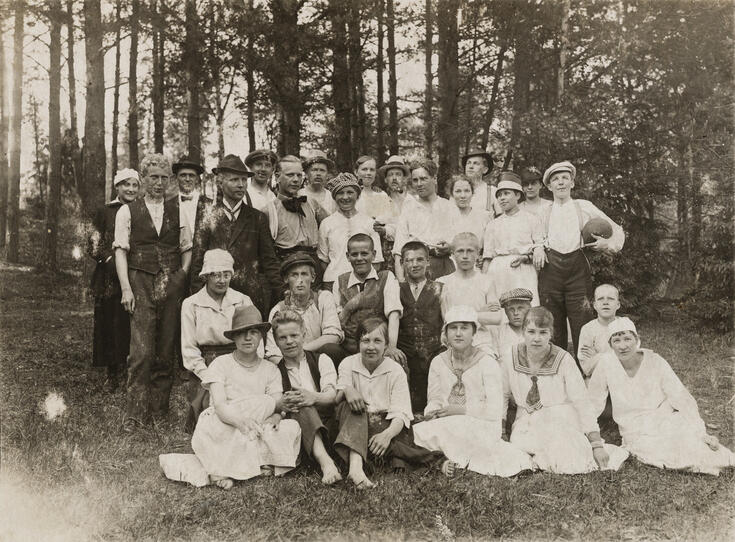 Finklädda människor som har samlats för att ta ett gruppfoto på en gräsmatta.