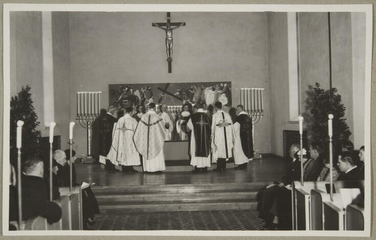 Biskopar står vid altaret med ryggen mot fotografen. I vänstra och högra kanten syns publik i kyrkbänkarna.