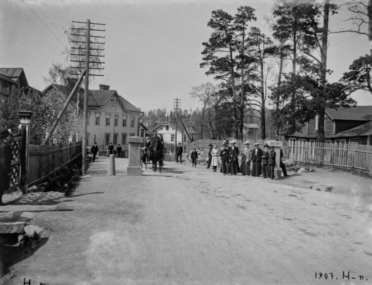 Folk vid stadens tullport på Östra Chaussén (nuvarande Tavastvägen). Till höger Hermanstad 41, Edward Forsbäcks hus och pyrotekniska laboratorium.