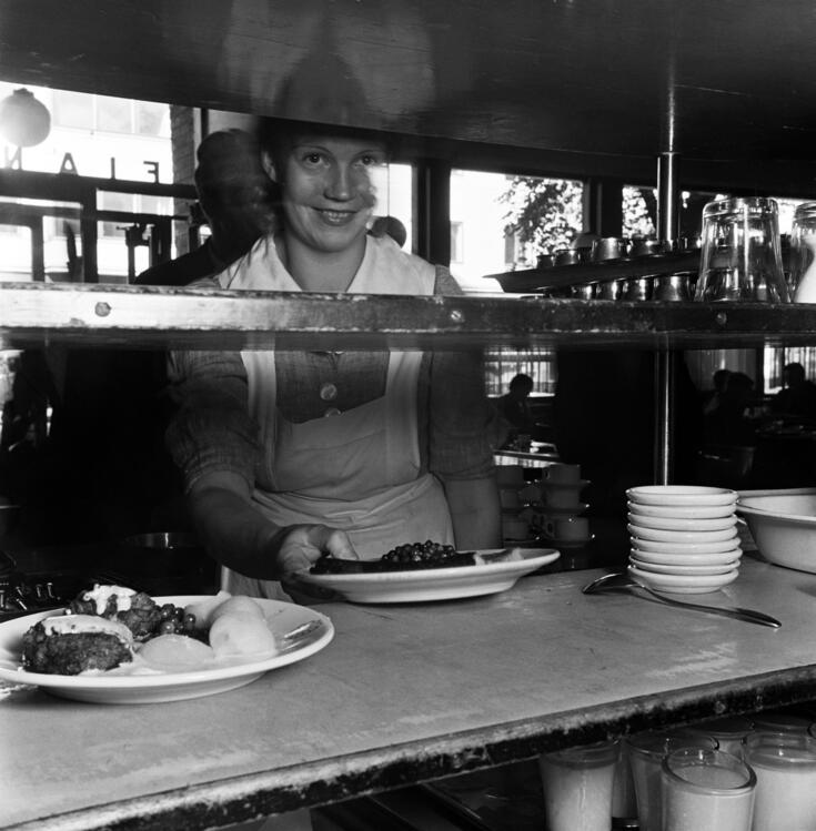 Elantos restaurang nr.  5, Tavastvägen 11. En kvinna serverar matportioner.