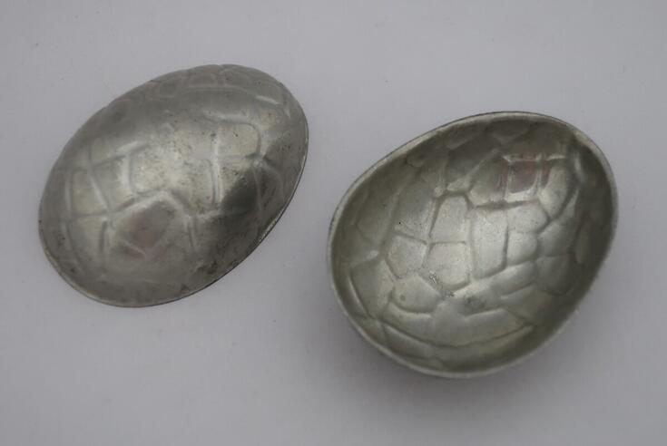 Två utåtbuktande plåtformar för tilverkning av chokladägg.