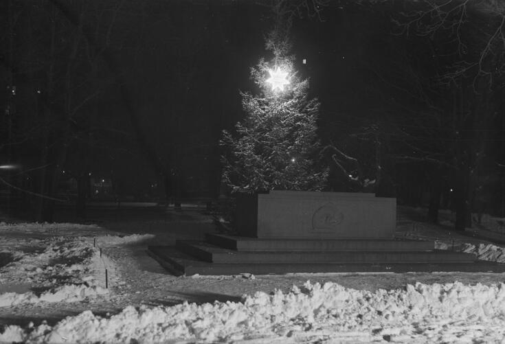 En minnessten som placerats på en stensockel med några trappsteg. På sidan av stenen har avbildats en mänskogestalt som sitter på huk vilande sitt huvud mot händerna.