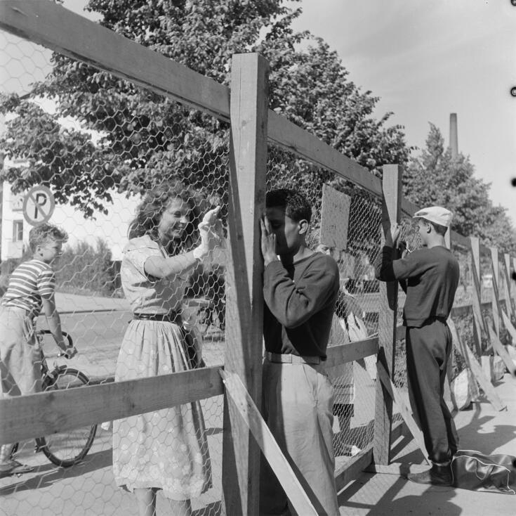 Helsingin olympialaiset 1952. Urheilijat jakavat nimikirjoituksia verkkoaidan takaa Käpylän Kisakylässä.