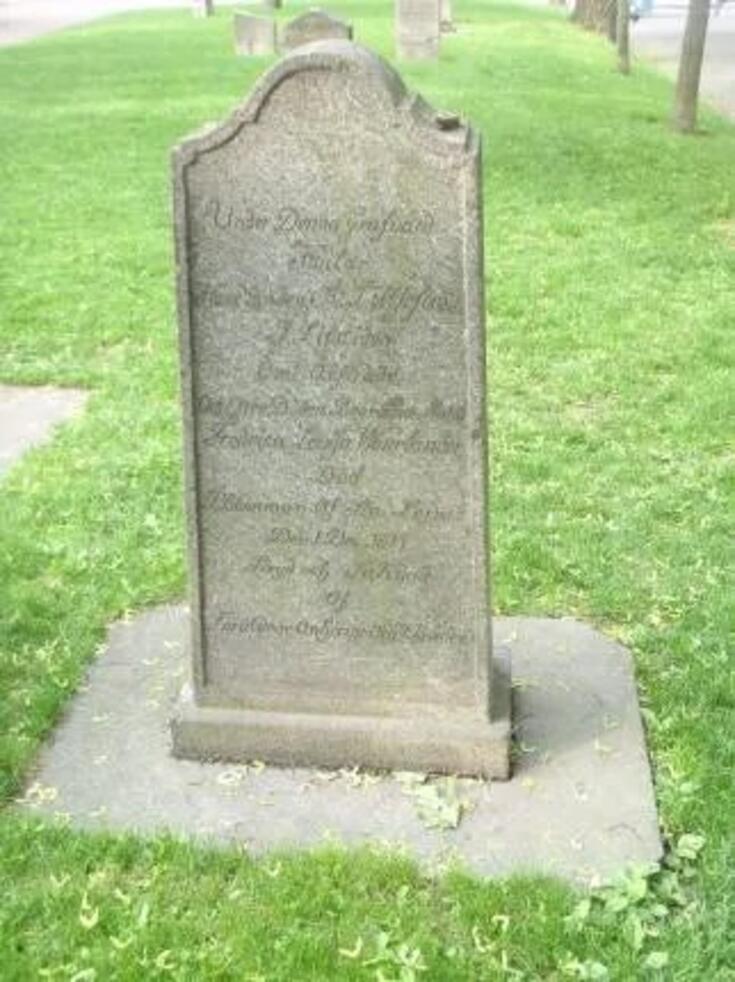 Hautapaasi, jonka ympärillä kasvaa ruohoa. 