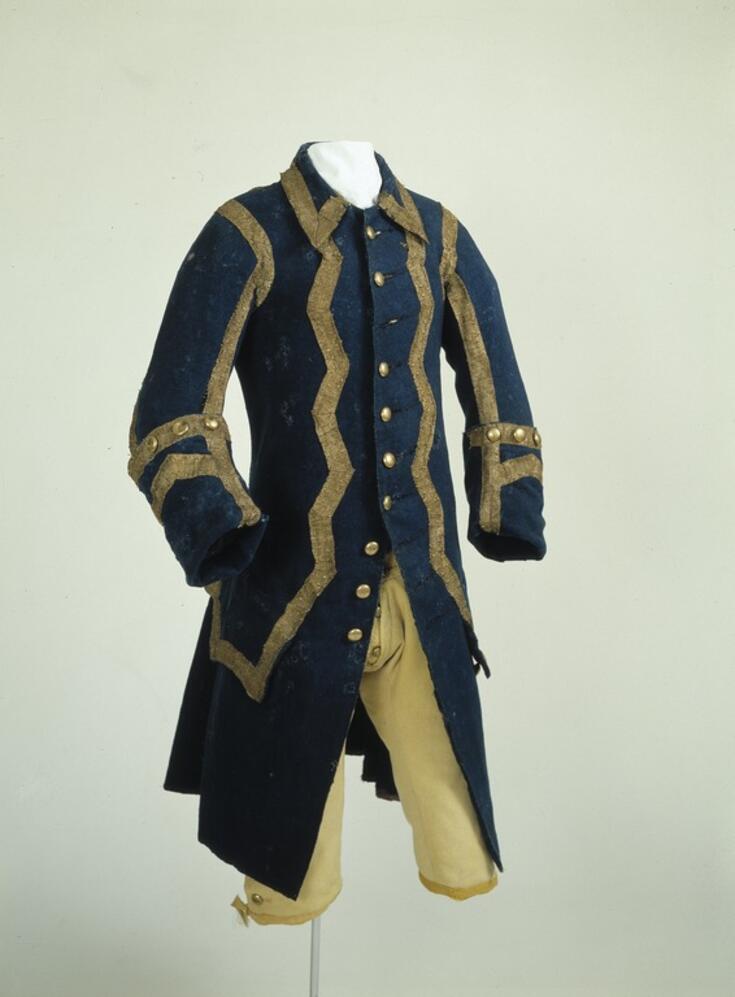 Uniform för trumslagaren och stadsutroparen i Helsingfors borgargarde. Den långa blåa yllerocken är rikligt dekorerad med guldfärgade band och knappar.