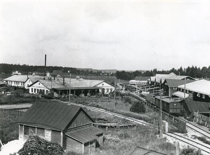 Matalia varasto- ja teollisuusrakennuksia, joiden välissä on rautatiekiskoja.