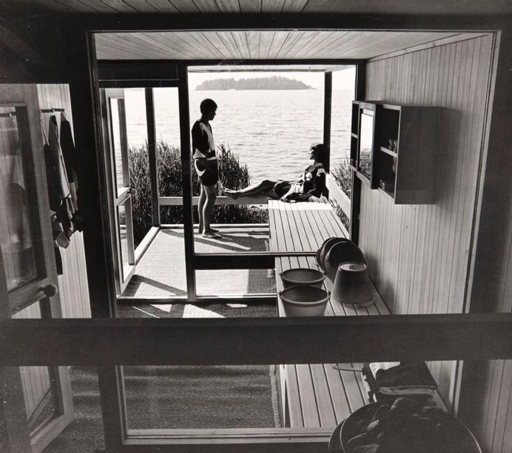 Interiör från bastun och två bastubadare på terrassen med ett havslandskap i bakgrunden.