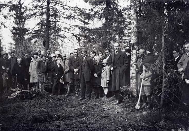 Ihmisiä kerääntyneenä muistojuhlaan metsässä