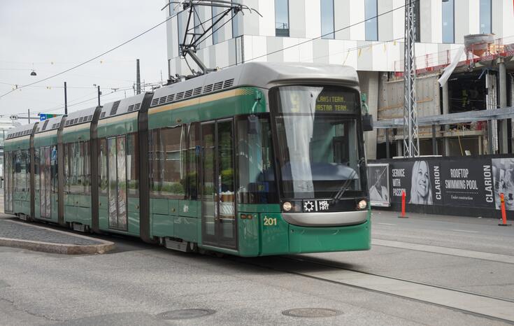 Vihreä raitiovaunu, jonka taustalla on hotelli