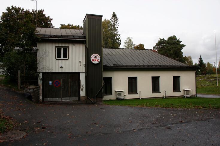 Bocksbacka frivilliga brandkårs byggnad i riktning från Eskosgränden. På byggnaden finns en rund skylt där det står Pukinmäen VPK i rött.