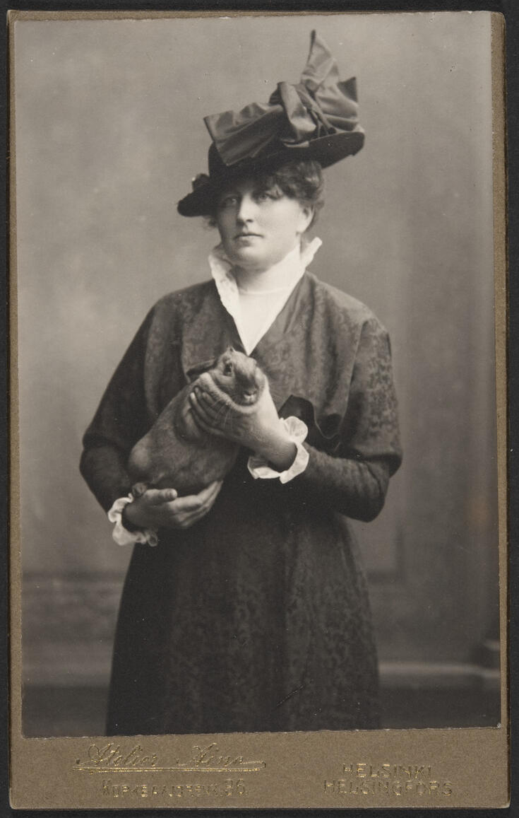 Takkiin ja hattuun pukeutunut nainen pitelee käsissään kania.