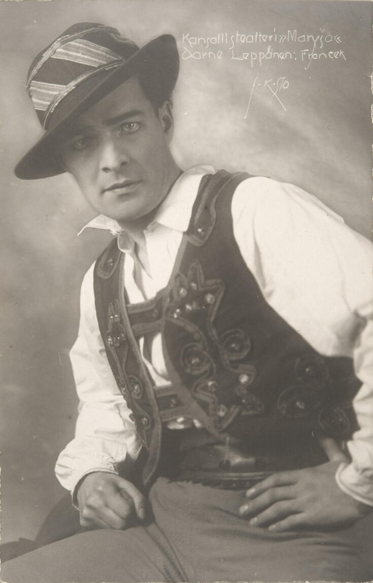 Rooliasuinen näyttelijä katsoo kameraan.