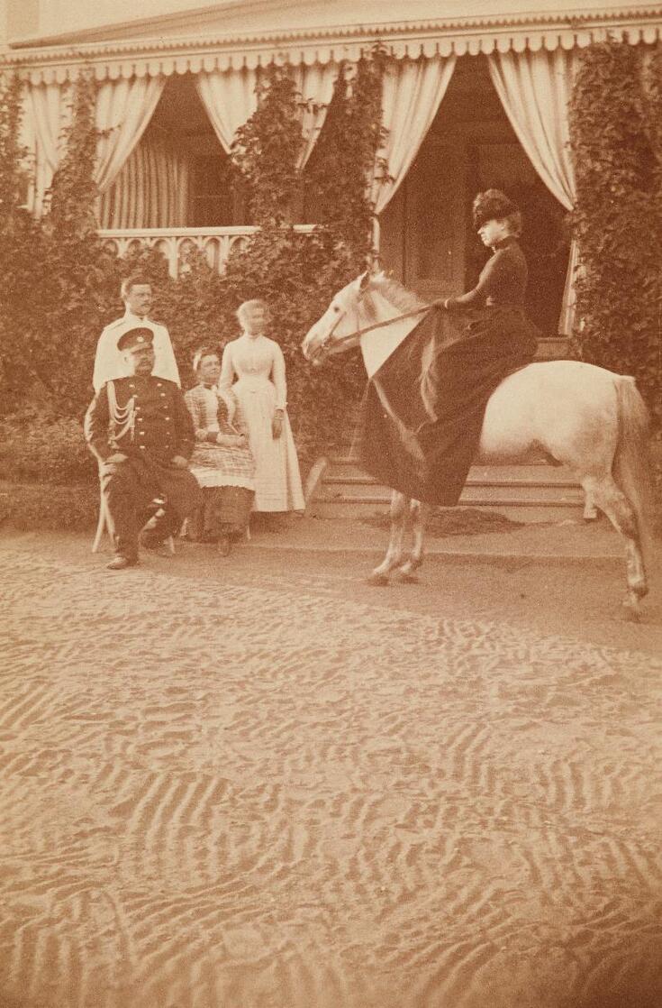 Friherren general Georg Edward Ramsay (1834–1918) och friherrinnan Elisabeth Ramsay, född Cumming, framför Munksnäs gård. Deras son Edward Aleksander (född 1862) står tillsammans med sin maka, Isabella Elisabeth (Isa) Rosinsky. Ramsays dotter Johanna Eleonora (Jane) (född 1863) till häst.