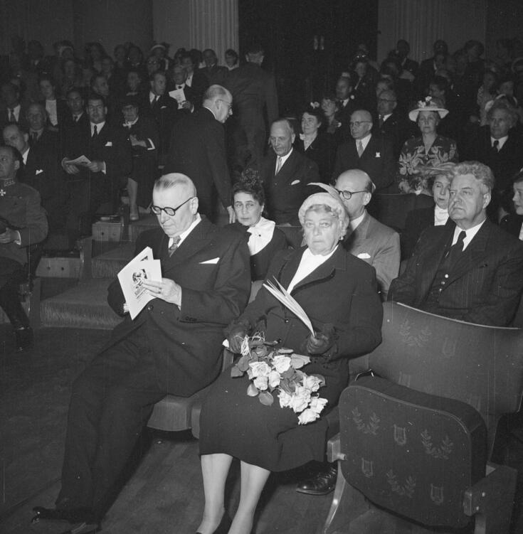 I förgrunden republikens president J. K. Paasikivi, som bläddrar i ett programblad, och fru Alli Paasikivi, som har en blombukett i famnen. Bakom dem statsminister Urho Kekkonen och fru Sylvi Kekkonen.