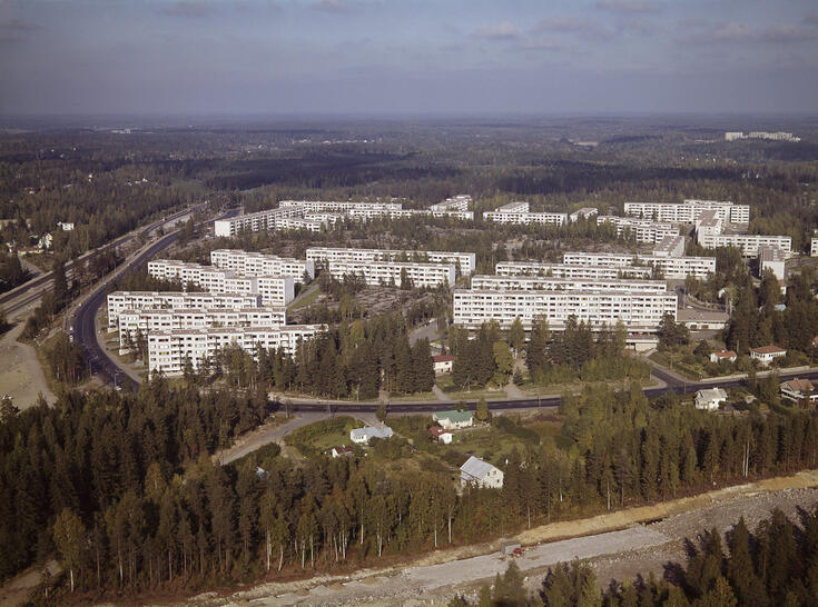 Keskellä kuvaa on kerrostaloalue. Ympärillä on pikkuteitä ja metsää sekä muutama omakotitalo.