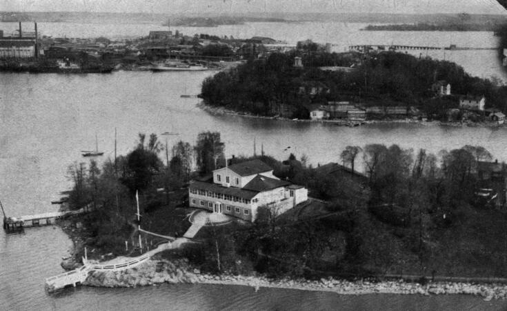 Edessä Suomalaisen Pursiseuran rakennus Nihtisaarella, pyöreällä Sompasaarella erottuu näkötorni saaren korkeimmalla kohdalla, saari oli osuusliike Elannon käytössä vuodesta 1921, siellä toimi Elannon työntekijöiden lasten kesäsiirtola. Taustalla on Sörnäisten satama-aluetta, oik. Kulosaaren silta.