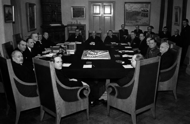 Miehiä istuu pöydän ääressä, pöydällä pienoismalli