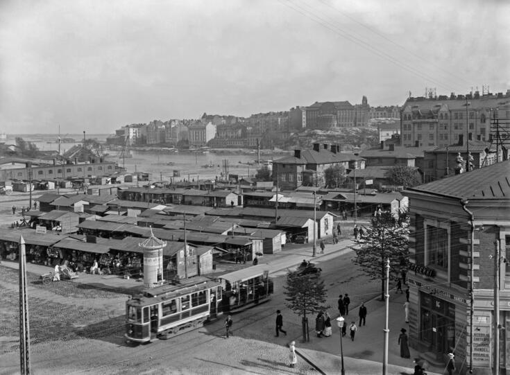 Hagnäs torg sett från nuvarande Cirkelhuset.  Det finns många försäljningsstånd på torget.  På förgrunden finns en spårvagn.