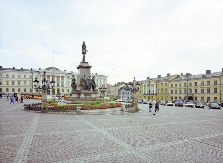 The Senate Square in 1995. The statue of Alexander II is in the foreground, with the Government Palace in the background. The buildings on Aleksanterinkatu on the right hand side include the City Hall.