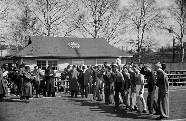 En grupp unga pojkar har ställt sig på startlinjen för en löptävling på Djurgårdsplanen.